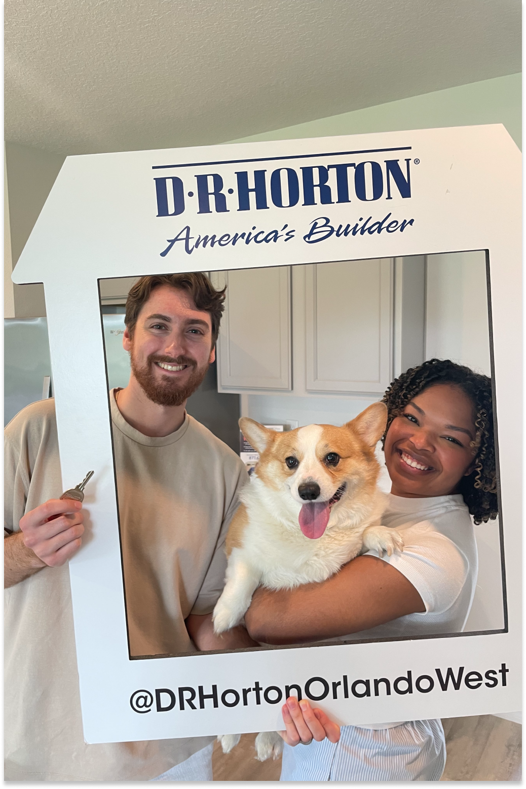 Zach and his wife holding their corgi in a D.R. Horton photo frame